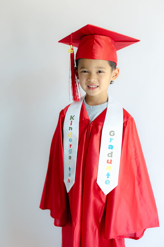 Child in cap and gown holding diploma for kindergarten photo shoot